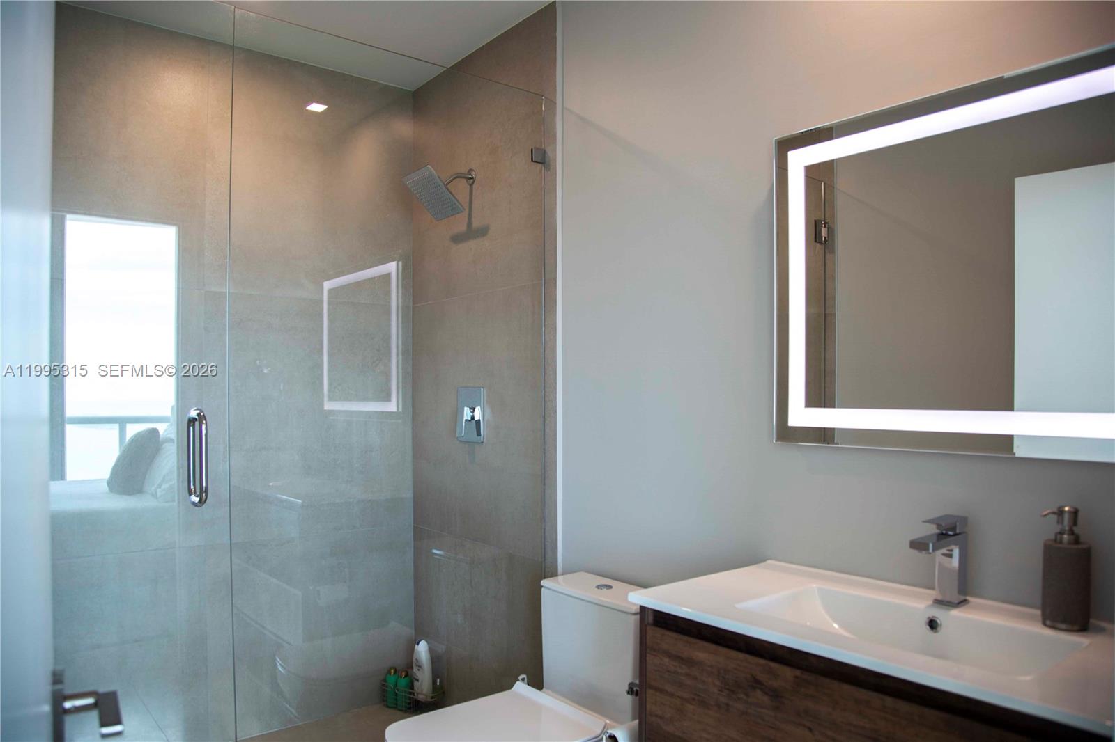 A modern bathroom features a glass-enclosed shower, a vanity with a sink, and a toilet — 888 Biscayne Blvd # 5207, Miami FL 33132, MIAMI, FL