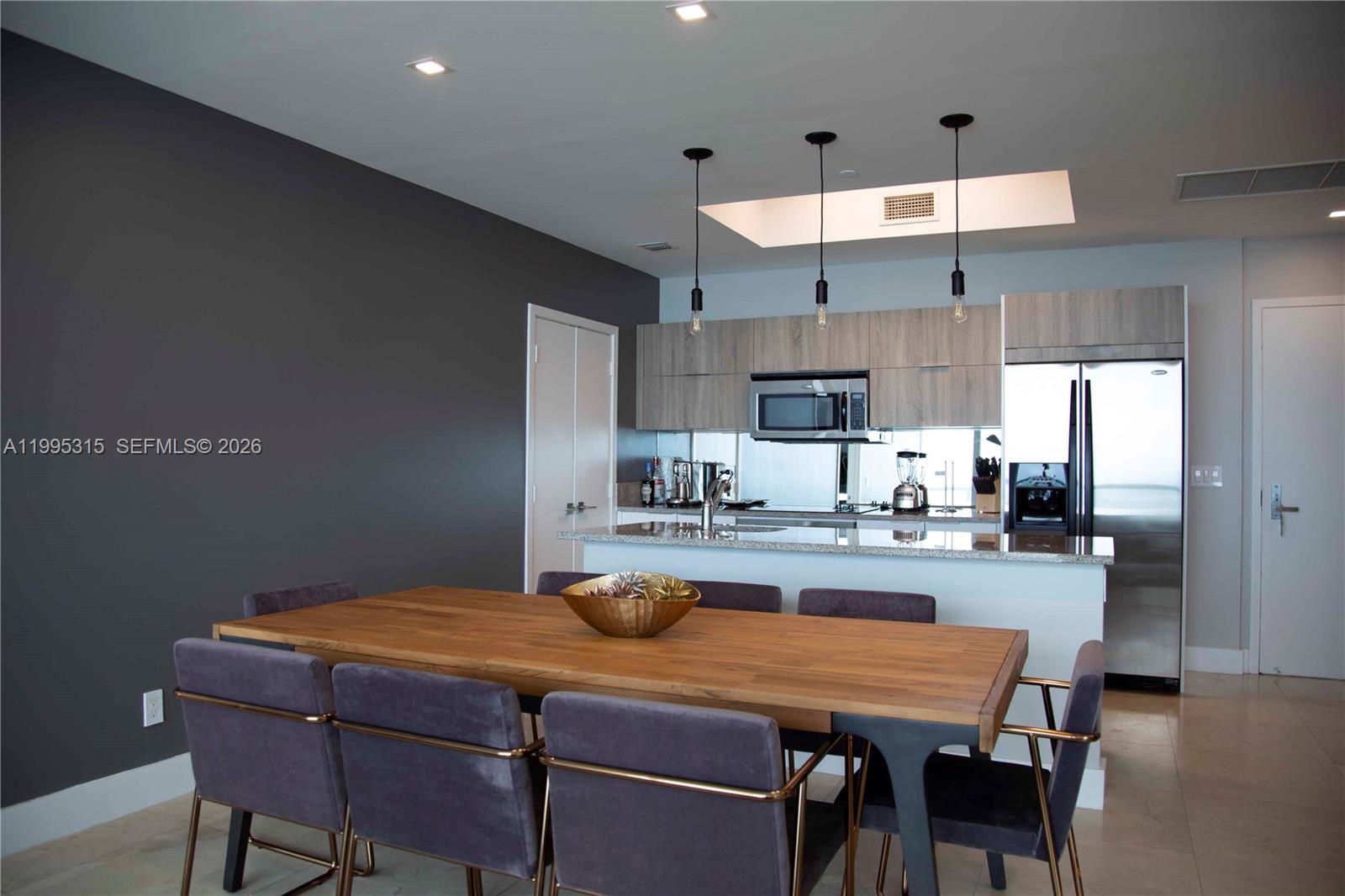 A dining area with a wooden table and chairs sits in front of a kitchen — 888 Biscayne Blvd # 5207, Miami FL 33132, MIAMI, FL