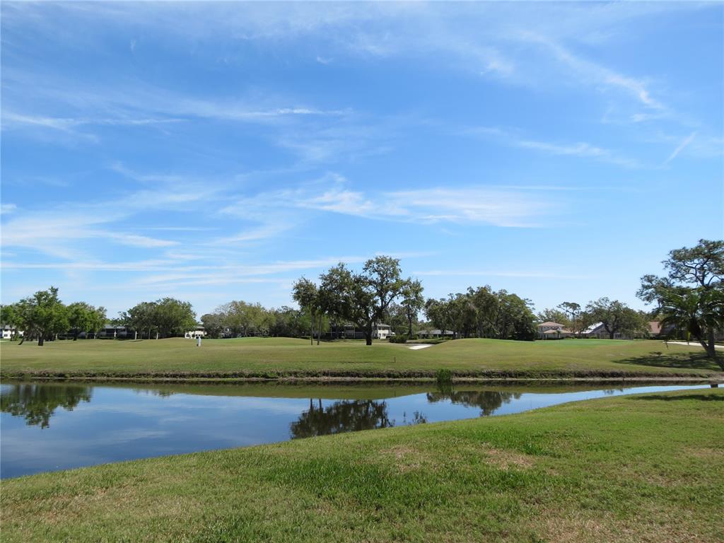 A view of a golf course fairway across a small pond under a blue sky — 7193 W COUNTRY CLUB DRIVE N UNIT 138, SARASOTA, FL