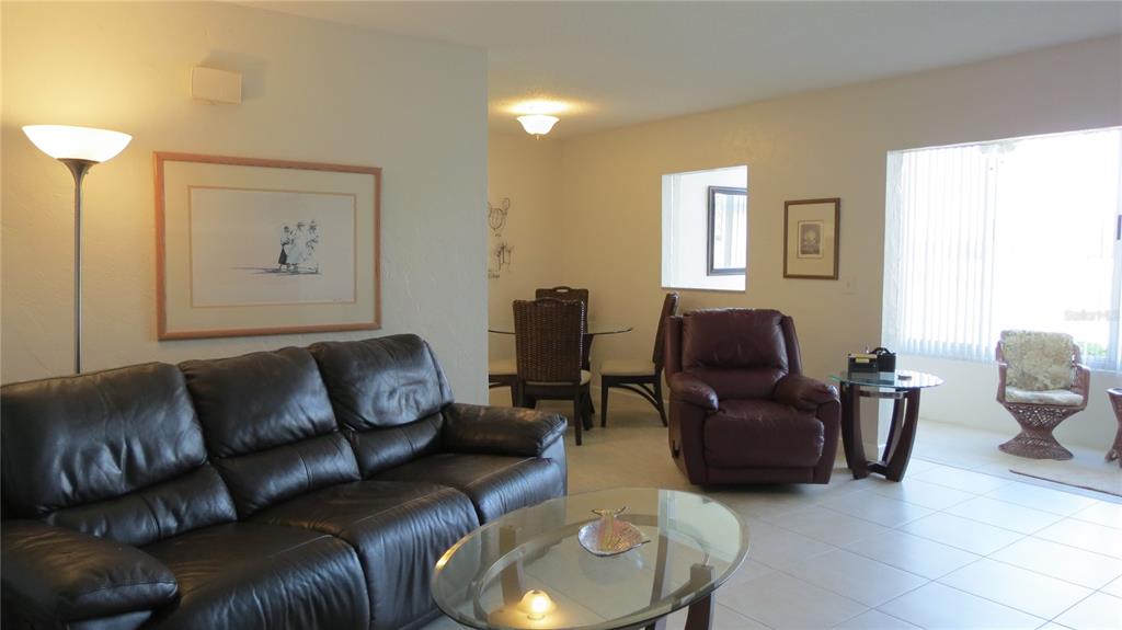 A living room with a dark leather sofa, recliner, and an adjacent dining area — 7193 W COUNTRY CLUB DRIVE N UNIT 138, SARASOTA, FL