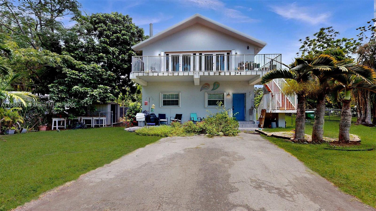 A two-story house with a balcony, exterior staircase, and a paved driveway in the yard — 18475 SW 204th St, Miami FL 33187, MIAMI, FL