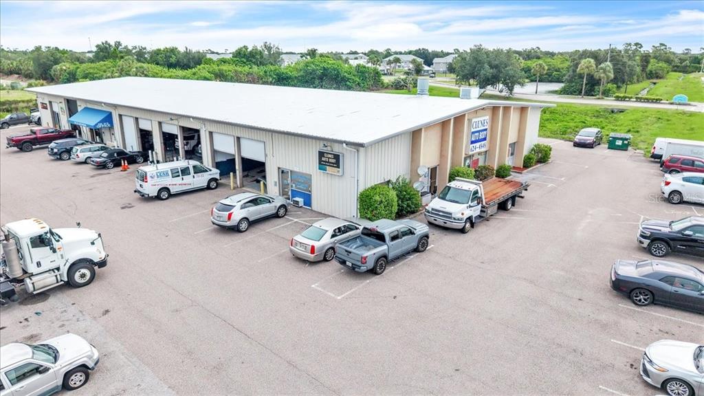 An aerial view shows an auto body shop building with a parking lot full of vehicles — 23415 JANICE AVENUE UNIT 22,23, PUNTA GORDA, FL
