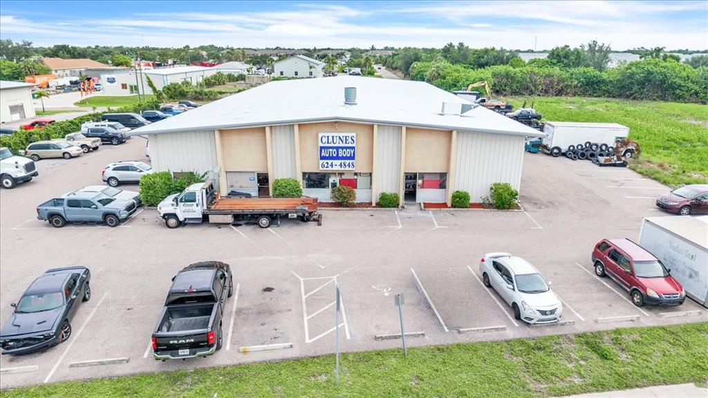An aerial view shows a commercial auto body shop building with a large parking lot — 23415 JANICE AVENUE UNIT 22,23, PUNTA GORDA, FL
