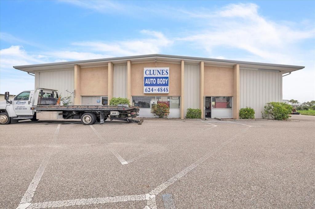 The exterior of a commercial building features a flat roof, tan walls, and a tow truck — 23415 JANICE AVENUE UNIT 22,23, PUNTA GORDA, FL