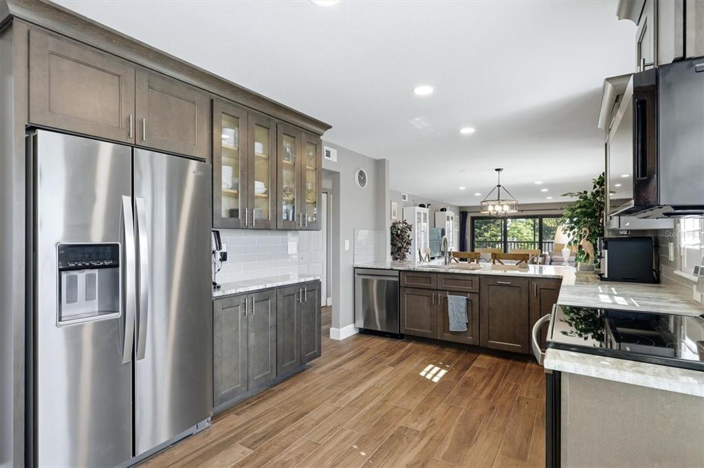 A modern kitchen features dark wood cabinets, stainless steel appliances, and wood-look tile flooring — 1001 BENJAMIN FRANKLIN DRIVE UNIT 206, SARASOTA, FL