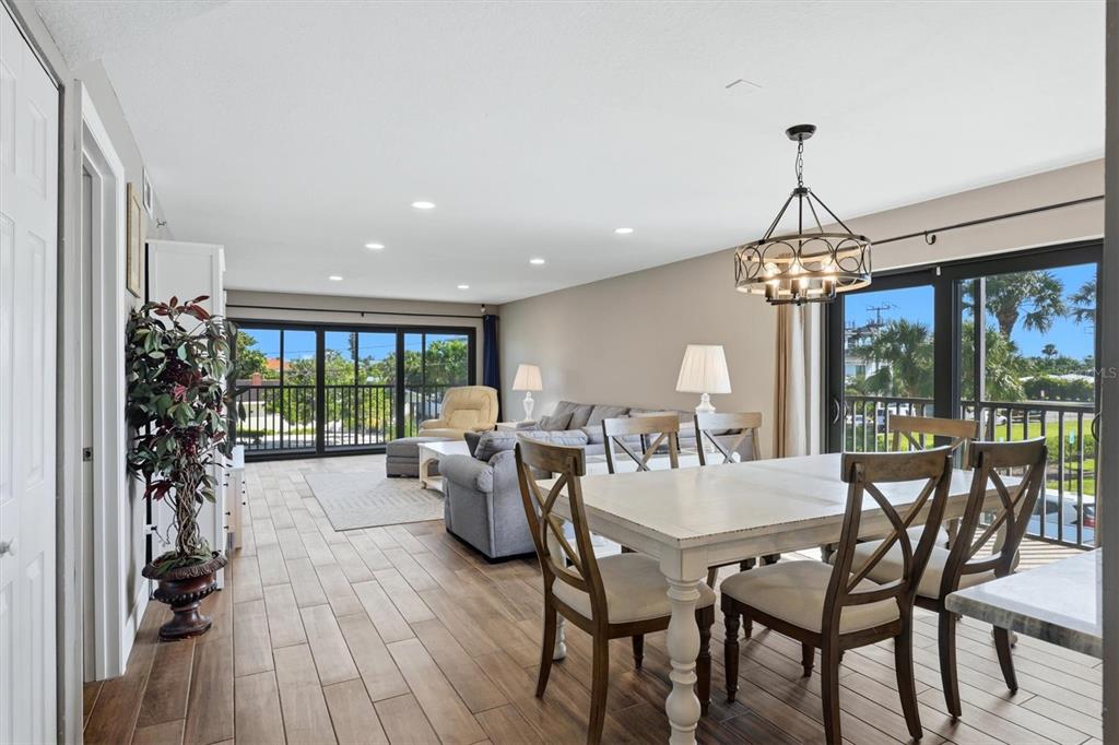 An open-concept living and dining area with wood-look tile flooring and sliding glass balcony doors — 1001 BENJAMIN FRANKLIN DRIVE UNIT 206, SARASOTA, FL