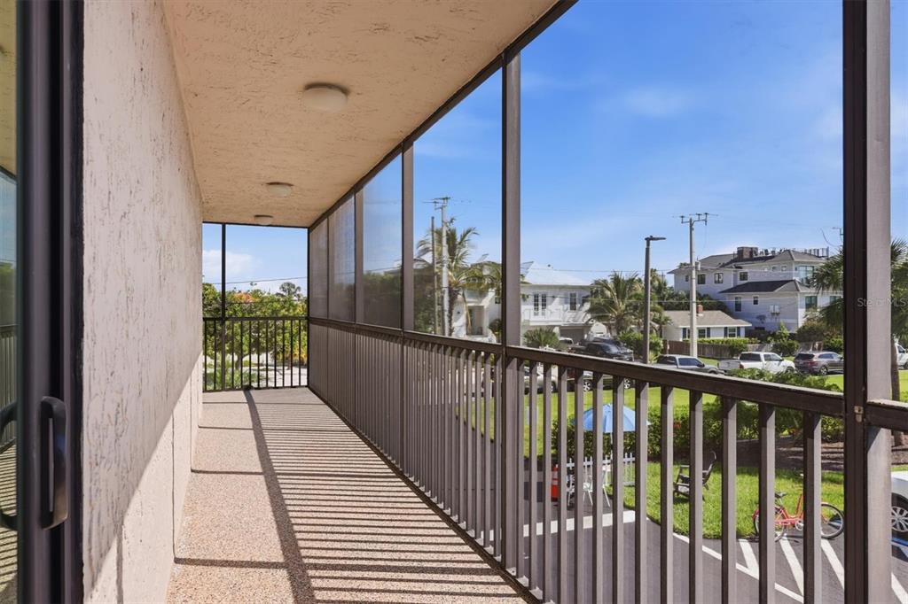 A screened-in balcony with a textured ceiling and metal railings overlooks a parking lot — 1001 BENJAMIN FRANKLIN DRIVE UNIT 206, SARASOTA, FL