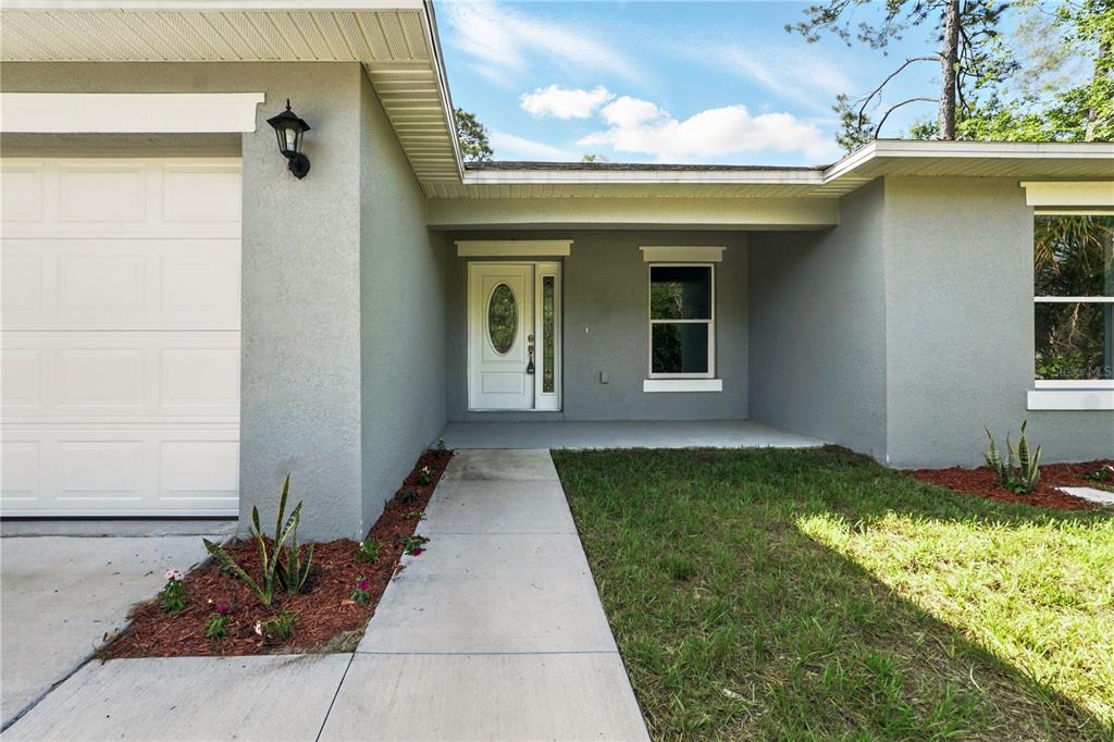 The exterior of a house features a white garage door, a front entrance, and landscaping — 225 STARLING COURT, KISSIMMEE, FL