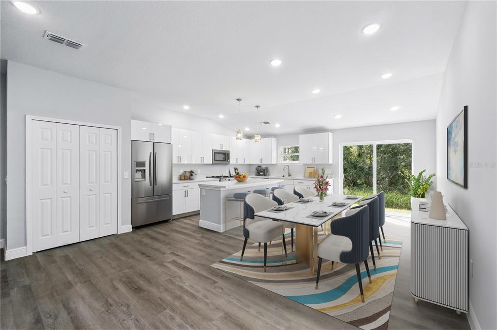 A bright, open-concept kitchen and dining area with white cabinetry, stainless appliances, and wood flooring — 225 STARLING COURT, KISSIMMEE, FL