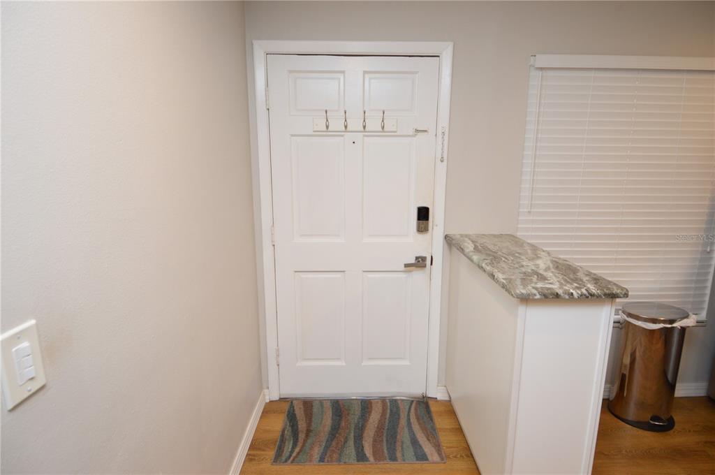 An entryway features a white front door with a coat rack, wood flooring, and a counter — 12760 INDIAN ROCKS ROAD UNIT 1034, LARGO, FL