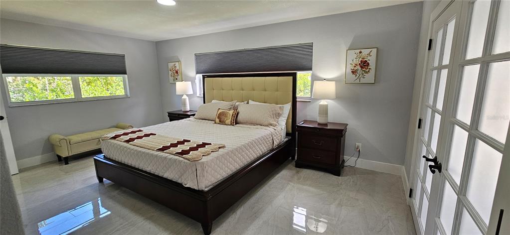 A bedroom features a tufted headboard, two nightstands, a bench, and tile flooring — 251 SE 46TH STREET, CAPE CORAL, FL