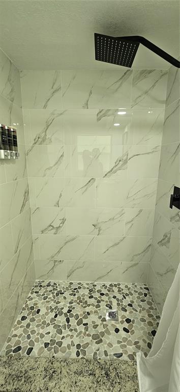A walk-in shower features white marble-look wall tiles, a pebble floor, and a black showerhead — 251 SE 46TH STREET, CAPE CORAL, FL