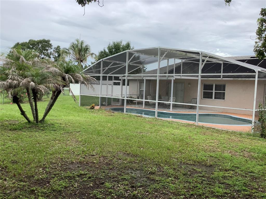 A backyard features a swimming pool enclosed by a screen cage next to a house — 665 STEVELYNN CIRCLE, WINTER GARDEN, FL