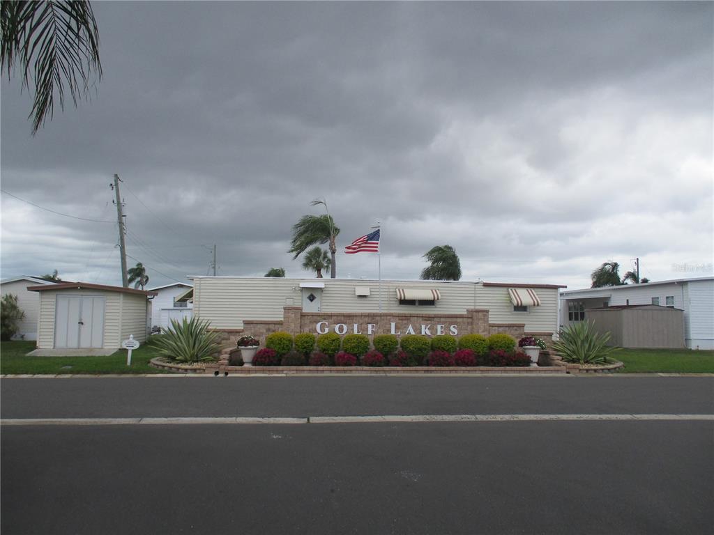 The exterior of a mobile home community entrance features a brick sign labeled Golf Lakes — 5009 8TH B STREET E, BRADENTON, FL
