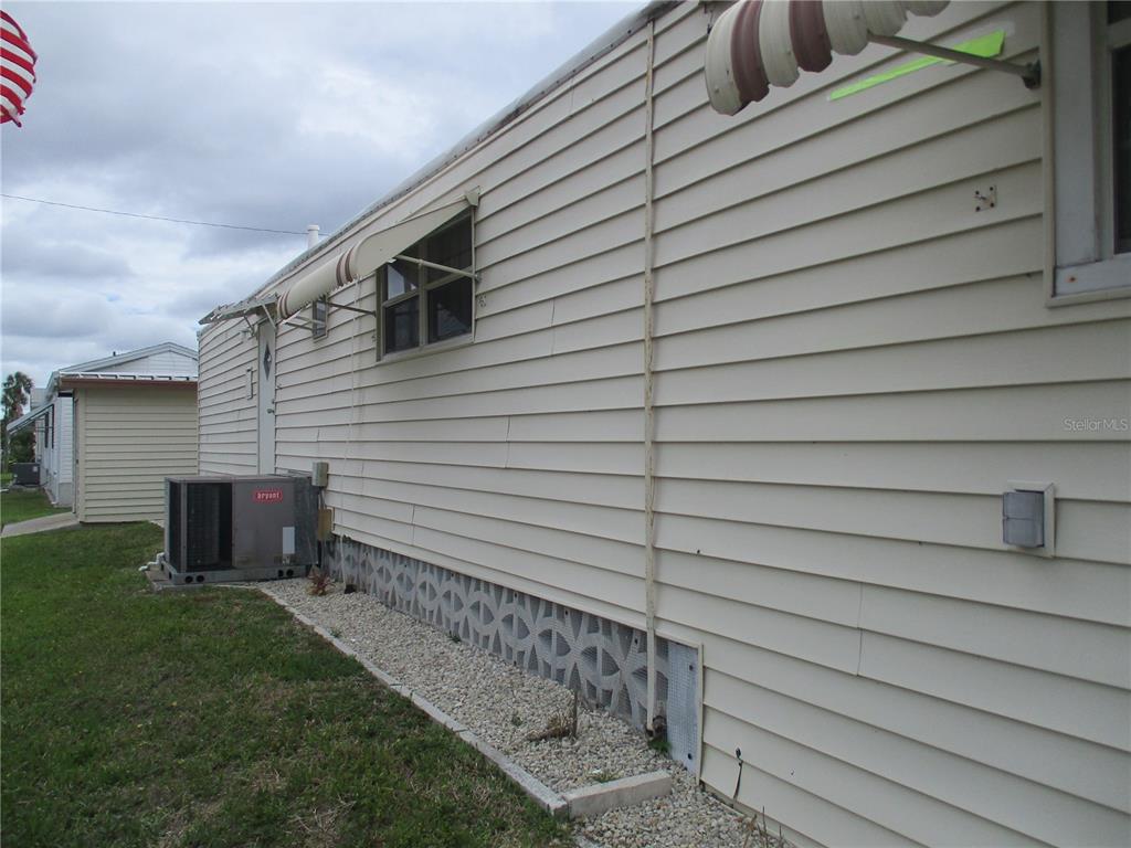 The exterior side of a mobile home features light-colored horizontal siding and a decorative block foundation — 5009 8TH B STREET E, BRADENTON, FL