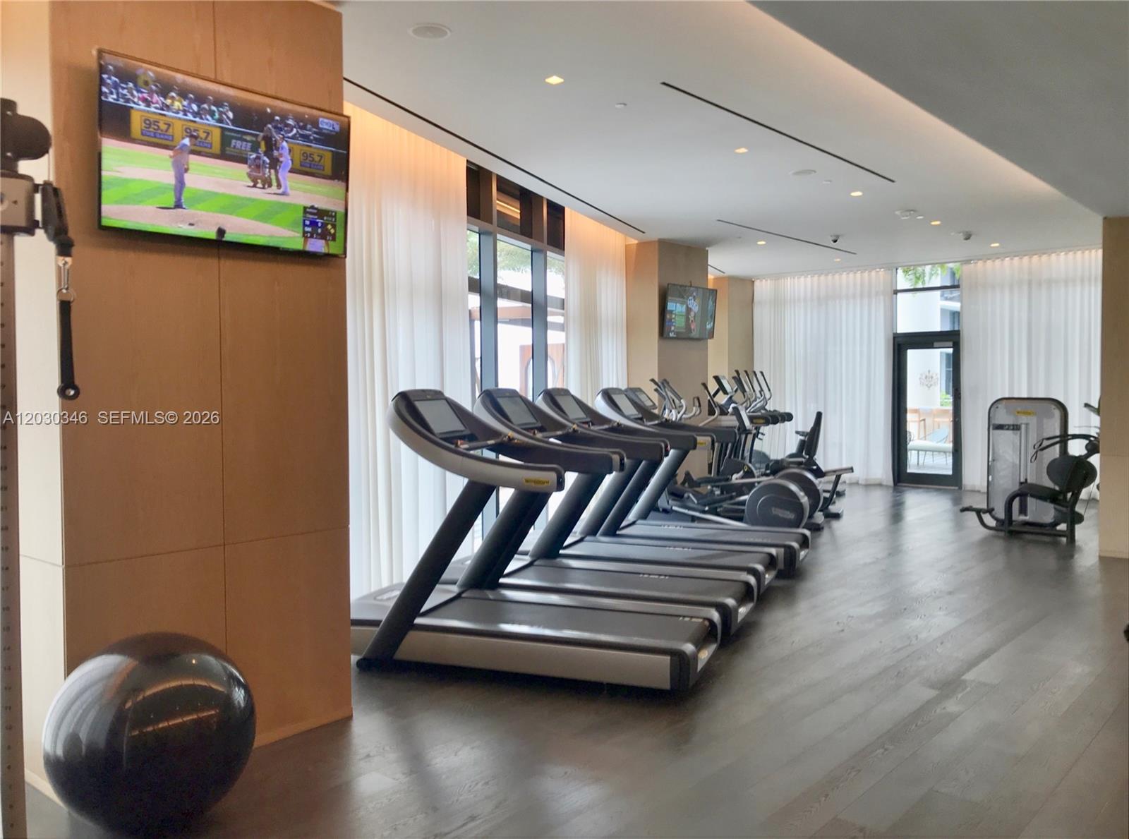 A modern fitness center features multiple treadmills, exercise equipment, and a wall-mounted television — 801 S Miami Ave # 1502, Miami FL 33130, MIAMI, FL