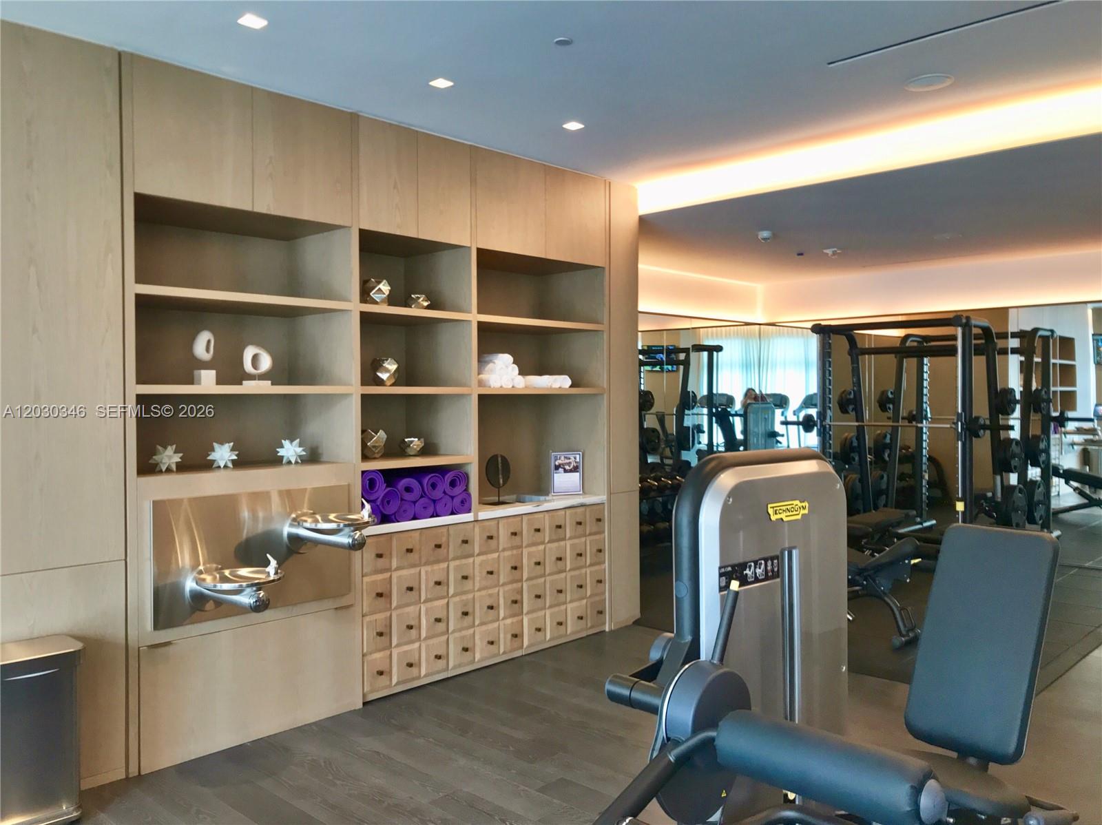 A modern gym features light wood cabinetry, a water fountain, and various exercise equipment — 801 S Miami Ave # 1502, Miami FL 33130, MIAMI, FL