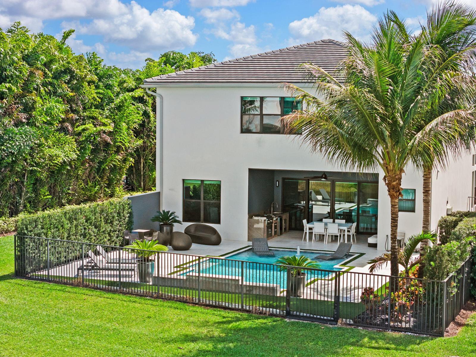 A two-story house features a backyard with a swimming pool, patio, and metal fence — 8599 Tower Bridge Court, Boca Raton FL 33496, BOCA RATON, FL