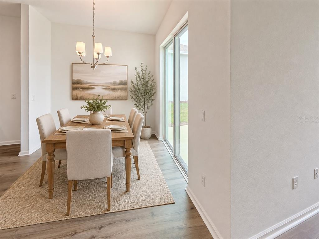 A dining room featuring a wooden table, six upholstered chairs, a chandelier, and sliding doors — 6213 SANDERS GROVE CIRCLE, OKAHUMPKA, FL