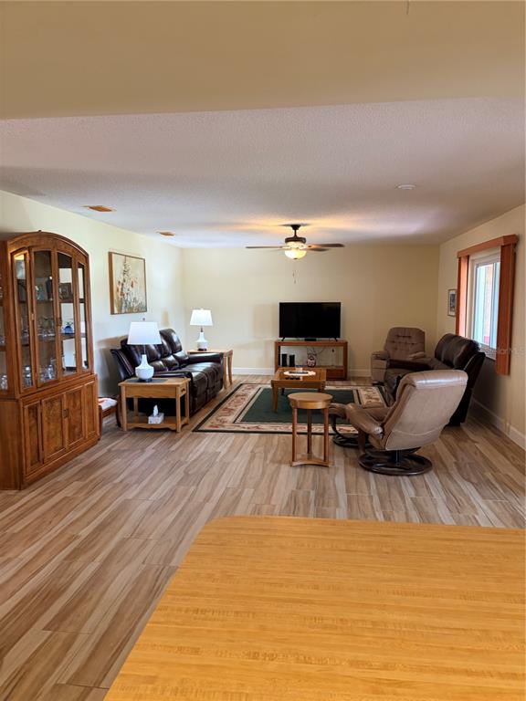 A living room with wood-look tile flooring, a ceiling fan, and a wooden hutch — 2117 HARLESTON UNIT 2117, SUN CITY CENTER, FL