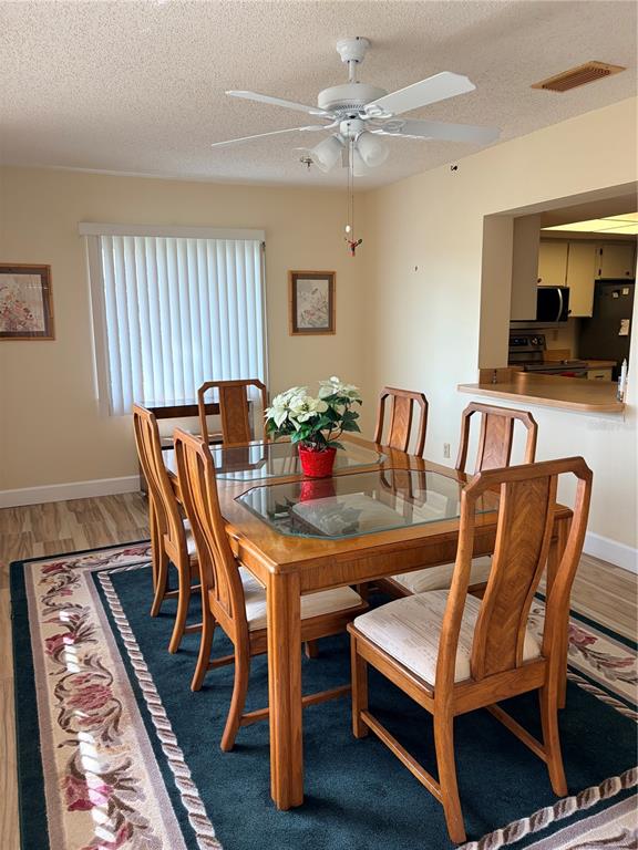 A dining room with a wooden table, six chairs, a ceiling fan, and a rug — 2117 HARLESTON UNIT 2117, SUN CITY CENTER, FL
