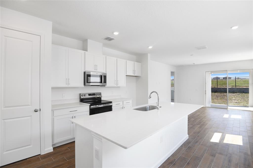 A modern kitchen features white cabinets, a central island with a sink, and tile flooring — 6373 CLOVER STREET, LAKE HAMILTON, FL