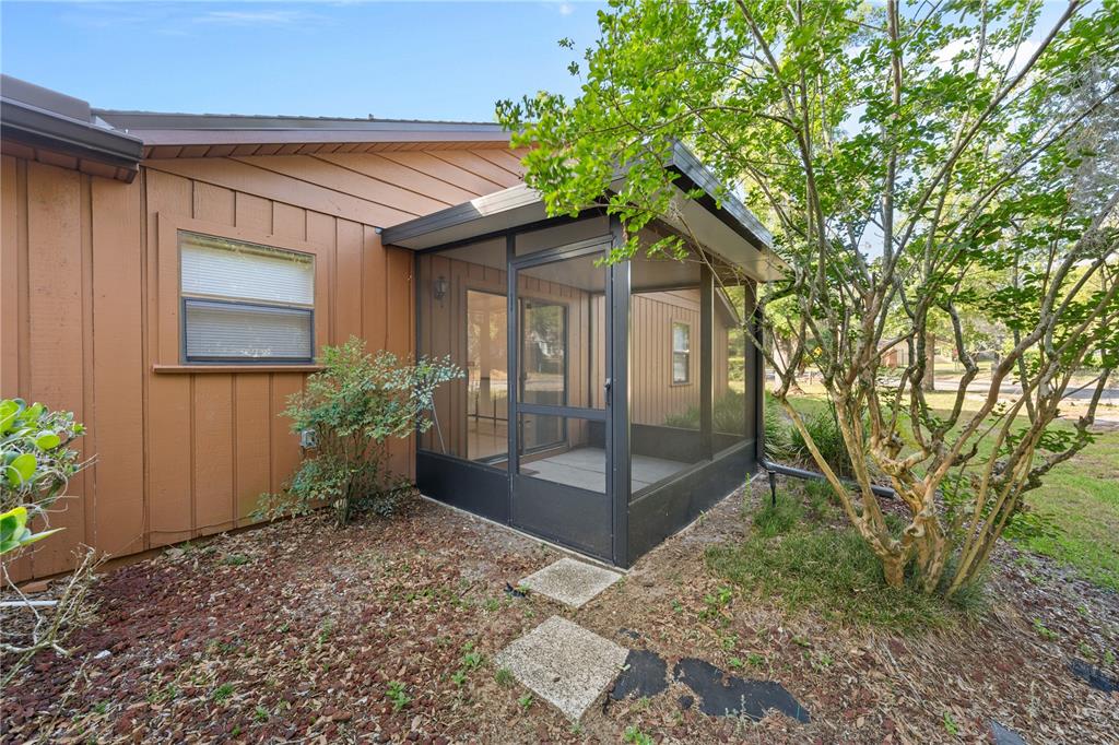A screened-in porch is attached to the side of a brown house with wood siding — 2701 NE 10TH STREET UNIT 101, OCALA, FL