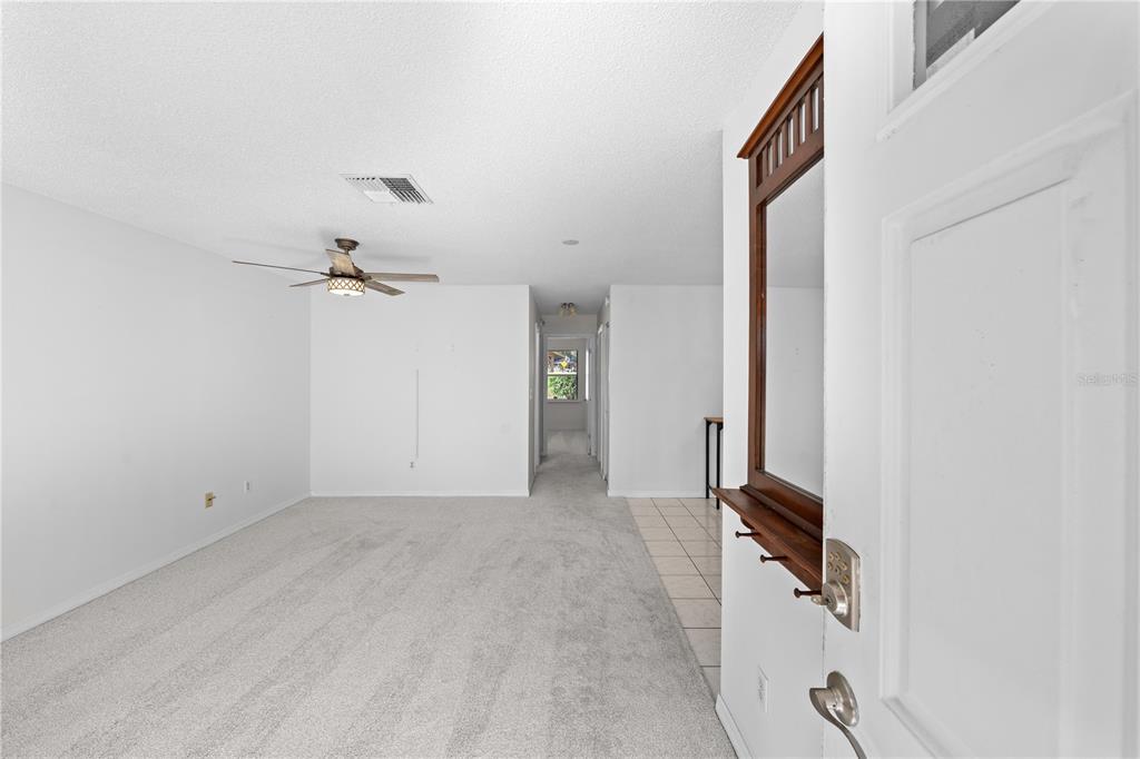 A view from an entryway into a carpeted living room with a ceiling fan — 2701 NE 10TH STREET UNIT 101, OCALA, FL
