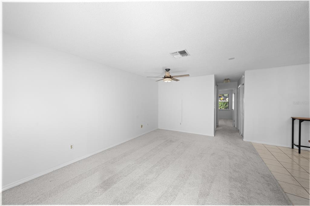 A living room with light gray carpet, white walls, and a ceiling fan — 2701 NE 10TH STREET UNIT 101, OCALA, FL