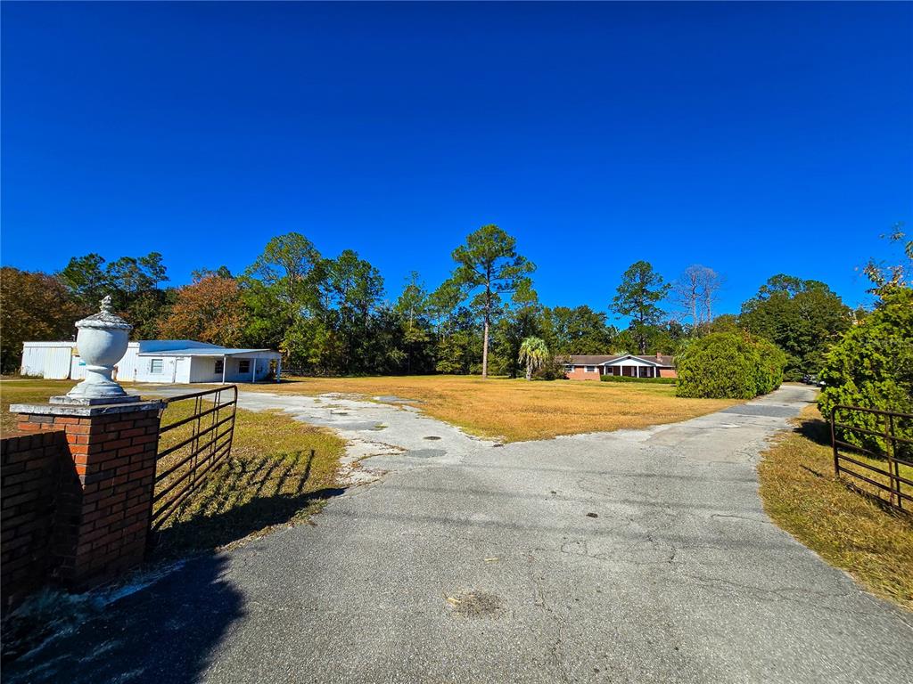 A paved driveway leads to a house and a detached building on a grassy lot — 11782 SW 59TH AVENUE, STARKE, FL