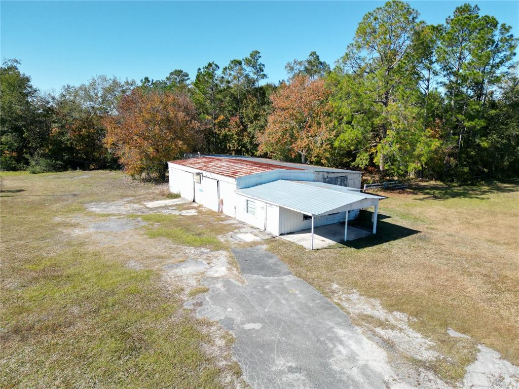An aerial view shows a white, single-story industrial building with a rusted metal roof — 11782 SW 59TH AVENUE, STARKE, FL