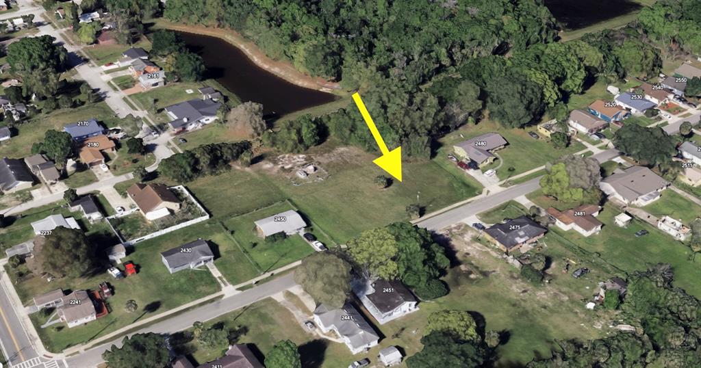An aerial view shows a vacant, grassy residential lot situated between existing houses and trees — CRAWFORD DRIVE, SANFORD, FL