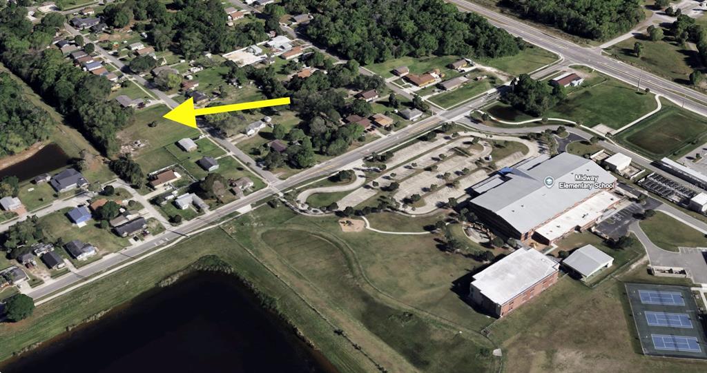 An aerial view shows a vacant residential lot marked by a yellow arrow near a school — CRAWFORD DRIVE, SANFORD, FL