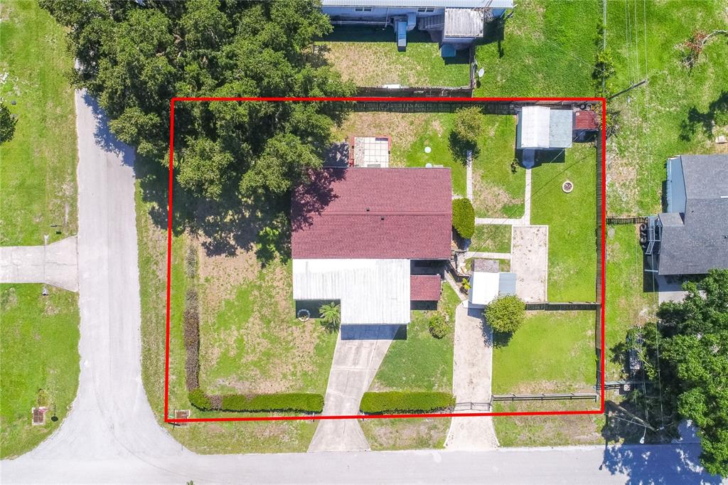 An aerial view shows a house with a red roof, a driveway, and a fenced yard — 2510 ISLAND OAKS E, LAKELAND, FL