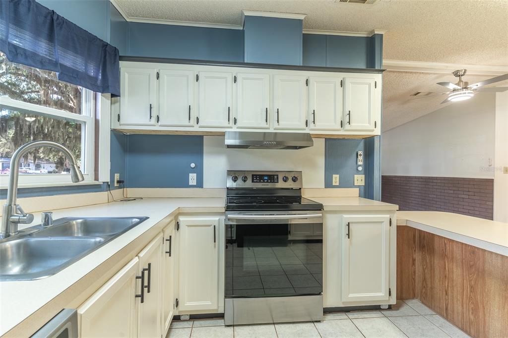 A kitchen features white cabinets, stainless steel appliances, blue walls, and a double basin sink — 2510 ISLAND OAKS E, LAKELAND, FL