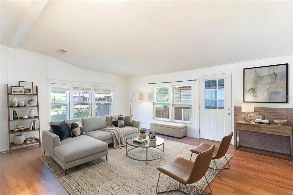 A living room features a grey sectional sofa, two leather chairs, and a brick accent wall — 2510 ISLAND OAKS E, LAKELAND, FL