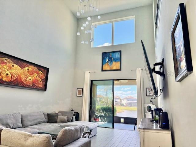 A living room with high ceilings, a large window, a sectional sofa, and wall art — 1131 WILDMEADOW RUN, WINTER PARK, FL