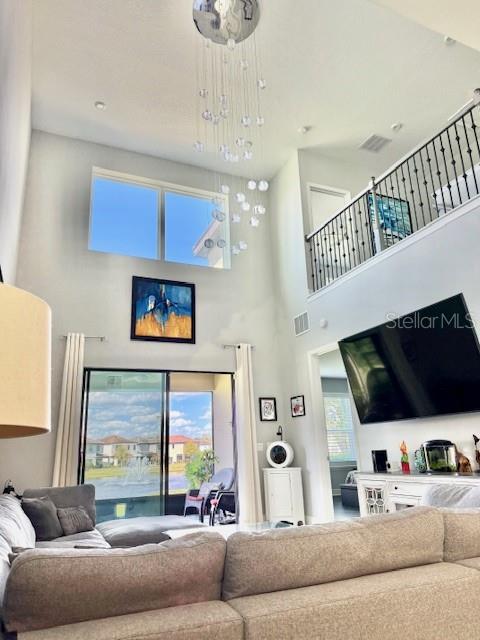A living room with a high ceiling, a large chandelier, and a view of a pond — 1131 WILDMEADOW RUN, WINTER PARK, FL