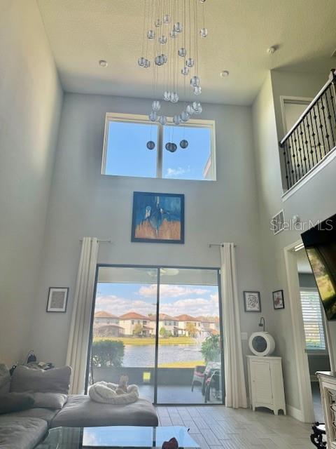 A high-ceilinged living room features a modern globe chandelier, large windows, and a sliding door — 1131 WILDMEADOW RUN, WINTER PARK, FL
