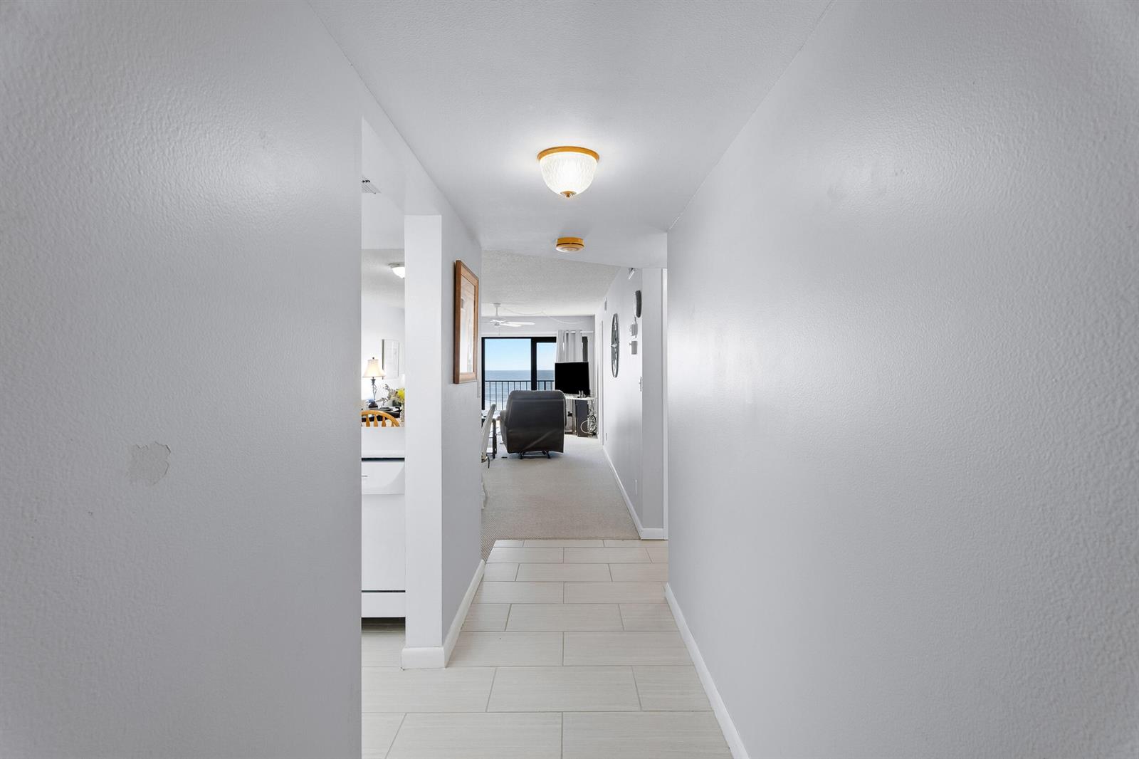 A hallway with light-colored tile flooring leads toward a living area with ocean views — 10310 S Ocean Drive # 609, Jensen Beach FL 34957, JENSEN BEACH, FL