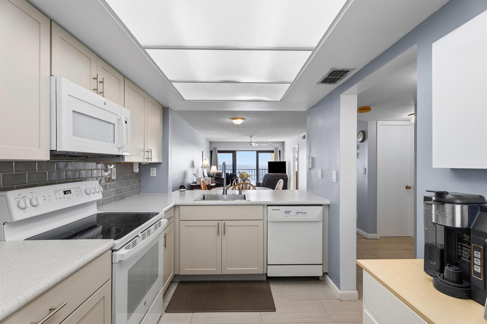 A kitchen with light-colored cabinets, a white stove, a dishwasher, and a view of the ocean — 10310 S Ocean Drive # 609, Jensen Beach FL 34957, JENSEN BEACH, FL