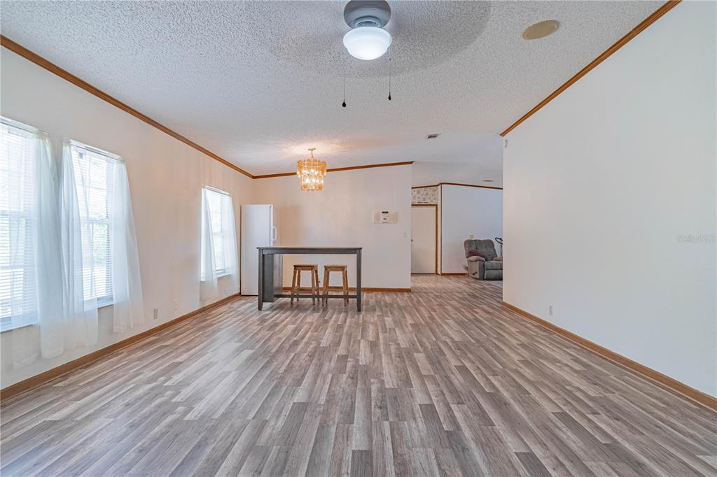 A spacious room with wood-look flooring, a ceiling fan, and a small dining area — 14800 HAYS ROAD, SPRING HILL, FL
