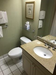 A bathroom features a white toilet, a vanity with a stone countertop, and a wall mirror — 36750 US HIGHWAY 19 N UNIT 6-212, PALM HARBOR, FL