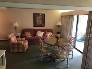 A living and dining area features a sofa, plaid armchair, and a round wooden table — 36750 US HIGHWAY 19 N UNIT 6-212, PALM HARBOR, FL