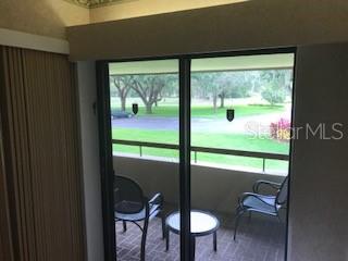 A view through a sliding glass door shows a balcony with two chairs and table — 36750 US HIGHWAY 19 N UNIT 6-212, PALM HARBOR, FL