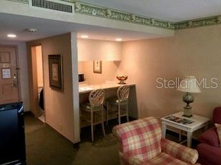A room features a small kitchen counter with two bar stools and a plaid armchair — 36750 US HIGHWAY 19 N UNIT 6-212, PALM HARBOR, FL