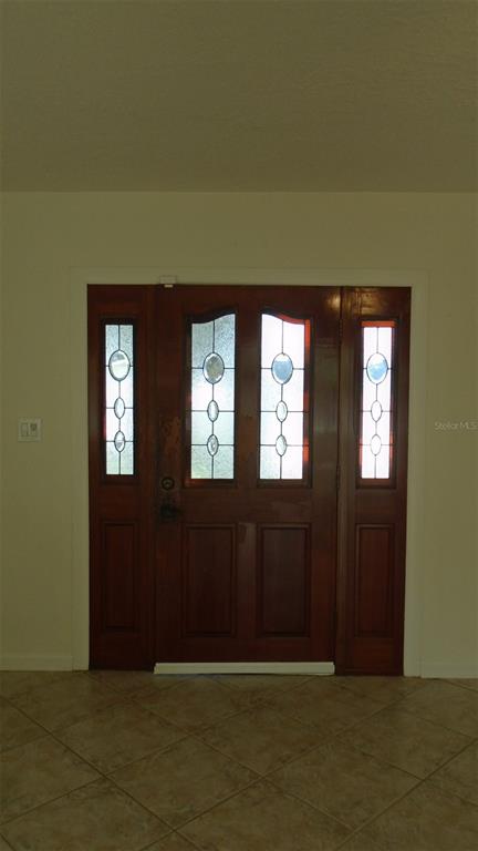 A wooden front door with glass inserts and side panels sits in a tiled entryway — 420 ARAPAHO TRAIL, MAITLAND, FL