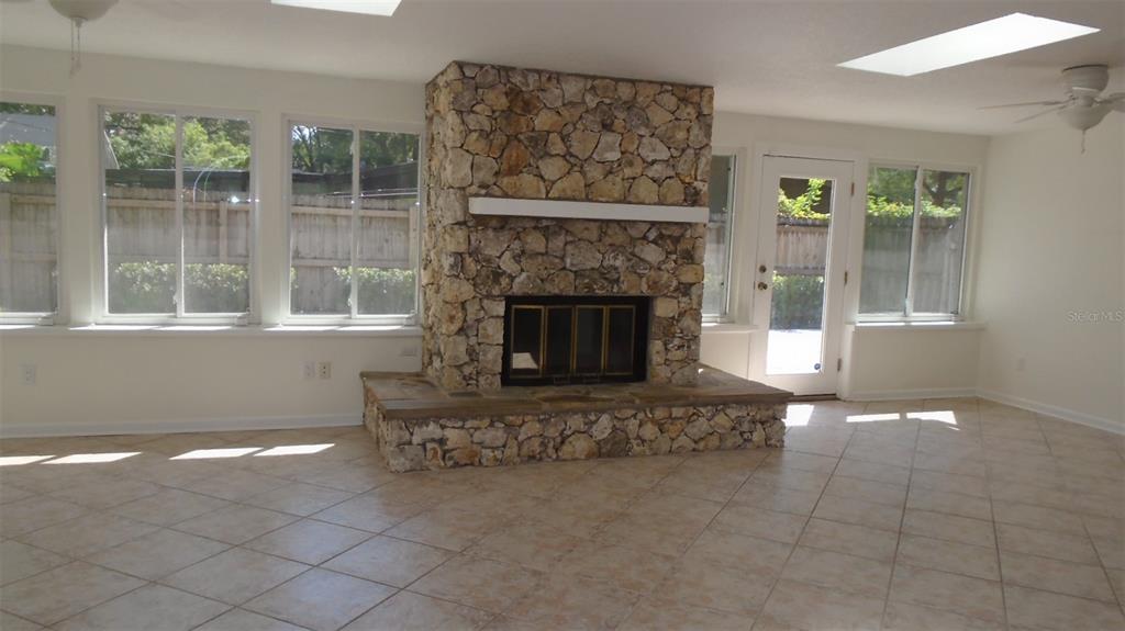 A sunroom features a large stone fireplace, tile flooring, and multiple windows — 420 ARAPAHO TRAIL, MAITLAND, FL