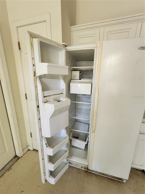 An open, white side-by-side refrigerator stands in a room with white cabinets and doors — 2102 ROTTWELL COURT, BRANDON, FL
