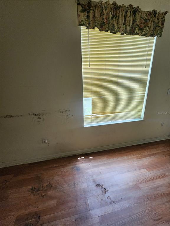 A room with wood-look flooring, a window with yellow blinds, and visible wall damage — 2102 ROTTWELL COURT, BRANDON, FL